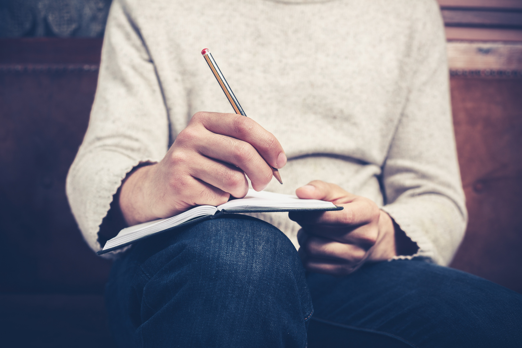 Man on sofa taking notes